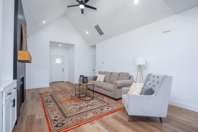 living room featuring high vaulted ceiling, a ceiling fan, light wood finished floors, baseboards, and visible vents