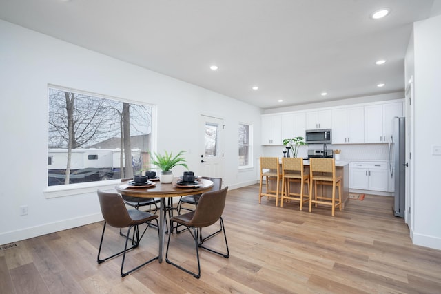 dining area with baseboards, light wood finished floors, and recessed lighting
