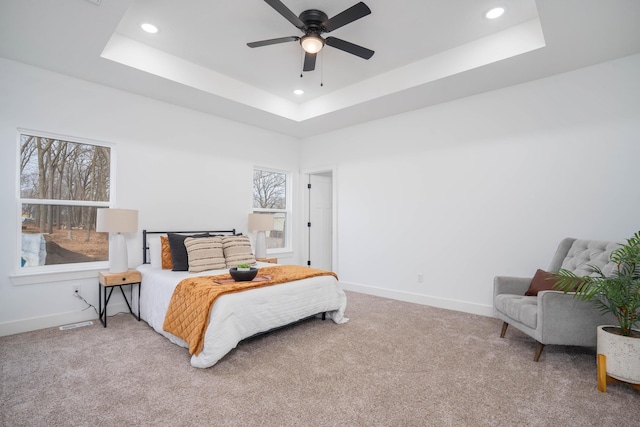 carpeted bedroom featuring baseboards, a tray ceiling, recessed lighting, and a ceiling fan