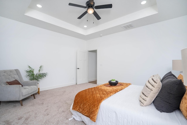 bedroom featuring light colored carpet, ceiling fan, and a tray ceiling