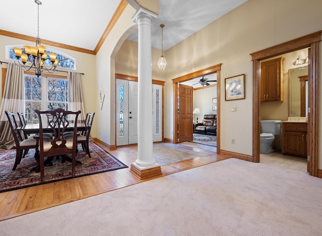 carpeted dining area featuring crown molding, a towering ceiling, decorative columns, and a notable chandelier