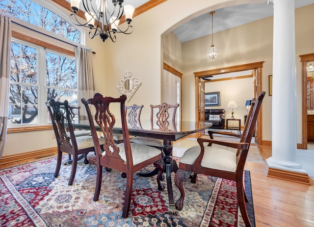 dining room featuring an inviting chandelier, crown molding, light hardwood / wood-style floors, and ornate columns