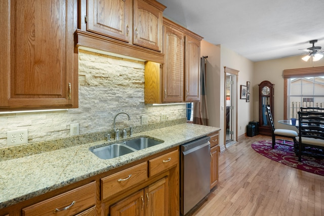 kitchen featuring sink, light stone counters, light hardwood / wood-style floors, decorative backsplash, and stainless steel dishwasher