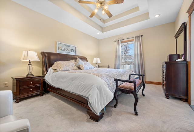 carpeted bedroom with ceiling fan and a tray ceiling