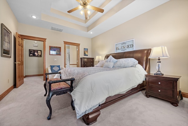 carpeted bedroom with a raised ceiling and ceiling fan