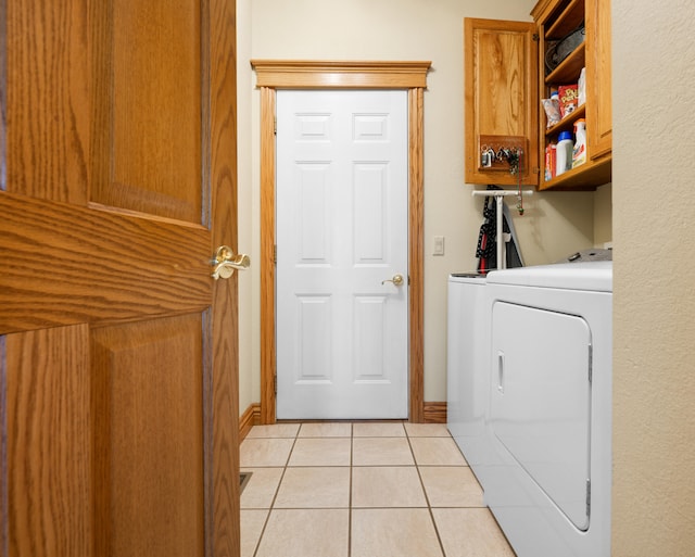 laundry room with cabinets, light tile patterned floors, and independent washer and dryer