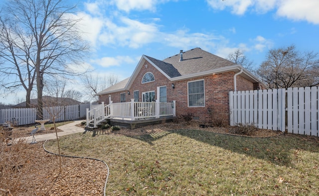 rear view of property featuring a deck and a lawn