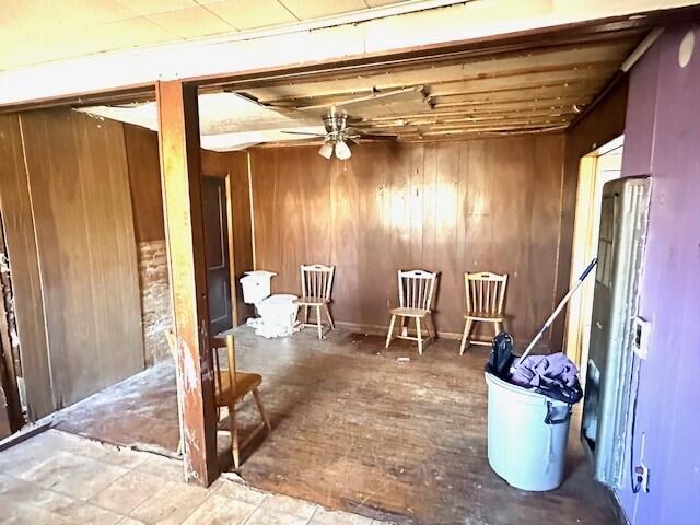 misc room featuring ceiling fan and wooden walls