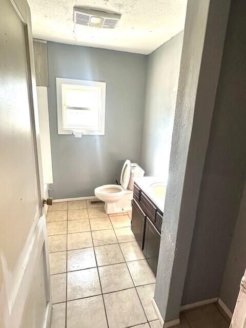 bathroom featuring vanity, tile patterned flooring, toilet, and a textured ceiling