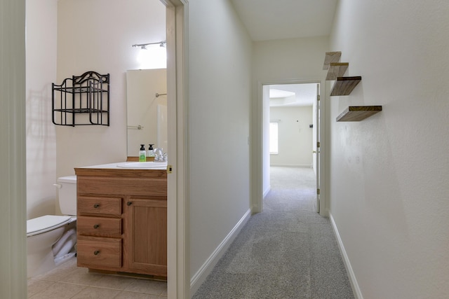 corridor featuring sink and light colored carpet