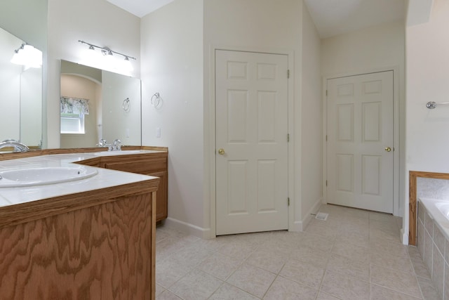 bathroom featuring tile patterned floors, tiled bath, and vanity