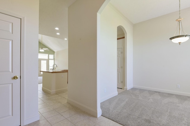 hallway featuring vaulted ceiling, sink, and light tile patterned floors