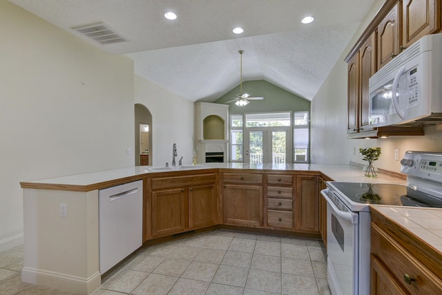 kitchen featuring sink, white appliances, tile counters, a textured ceiling, and vaulted ceiling