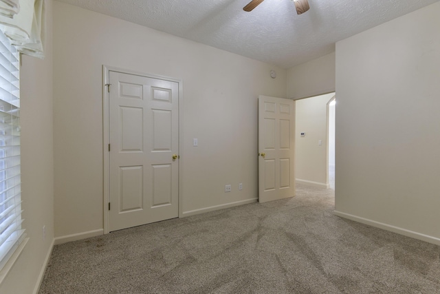 unfurnished bedroom featuring light carpet, a textured ceiling, and ceiling fan