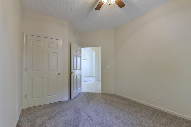 carpeted empty room featuring ceiling fan and a textured ceiling