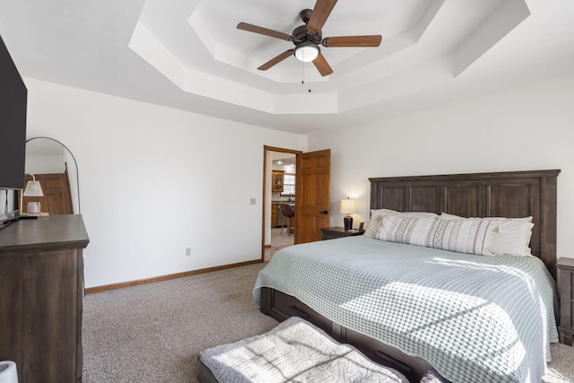 bedroom featuring ceiling fan, a tray ceiling, and light carpet