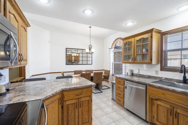 kitchen with sink, a chandelier, hanging light fixtures, light tile patterned floors, and appliances with stainless steel finishes