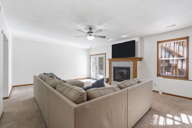 living room featuring a tiled fireplace, light colored carpet, and ceiling fan