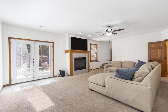 tiled living room featuring a tiled fireplace, french doors, and ceiling fan