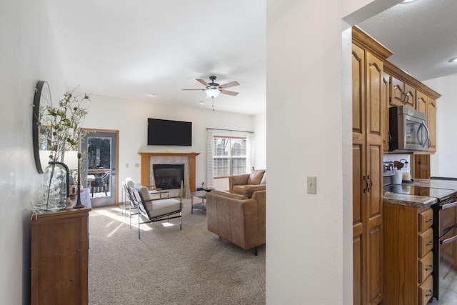 living room featuring ceiling fan, light colored carpet, and a fireplace