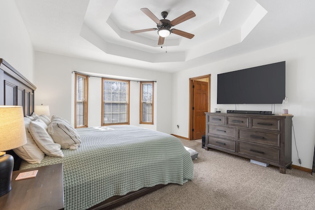 carpeted bedroom featuring ceiling fan and a tray ceiling