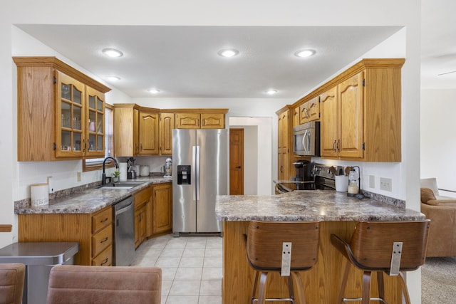 kitchen featuring light tile patterned flooring, a breakfast bar, sink, appliances with stainless steel finishes, and kitchen peninsula