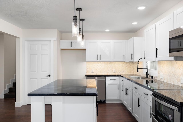 kitchen featuring appliances with stainless steel finishes, sink, a kitchen island, and white cabinets