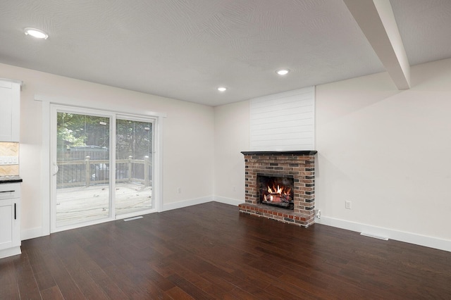 unfurnished living room featuring hardwood / wood-style floors, a textured ceiling, a fireplace, and beamed ceiling