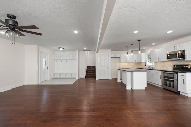 kitchen with pendant lighting, sink, appliances with stainless steel finishes, white cabinets, and a kitchen island