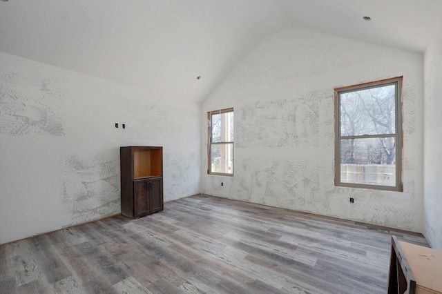 unfurnished room featuring plenty of natural light, high vaulted ceiling, and light wood-type flooring