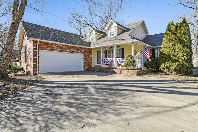 cape cod home featuring a garage and covered porch