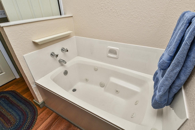 bathroom with wood-type flooring and a tub