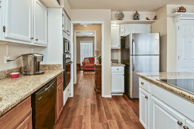 kitchen with dark hardwood / wood-style flooring, white cabinets, light stone counters, and black appliances