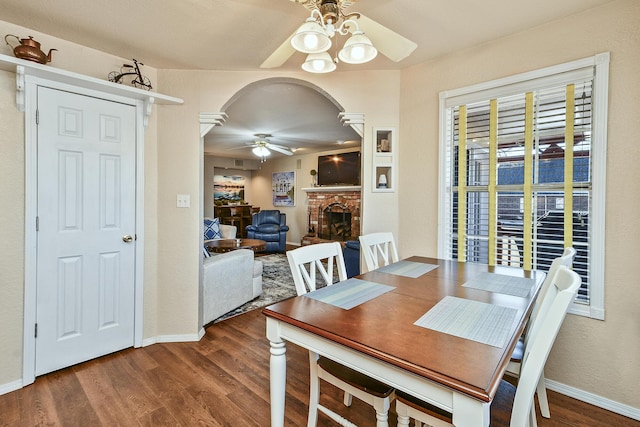 dining area with ceiling fan, hardwood / wood-style floors, and a brick fireplace