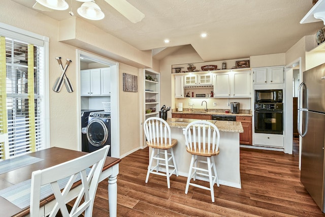 kitchen featuring sink, white cabinetry, a center island, light stone countertops, and black appliances