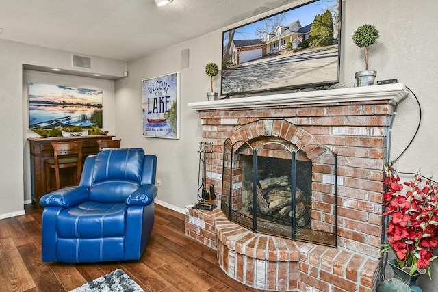 sitting room with a brick fireplace, dark hardwood / wood-style floors, and a textured ceiling