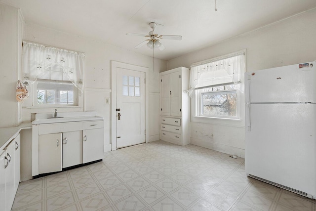 kitchen with white cabinetry, white fridge, sink, and ceiling fan