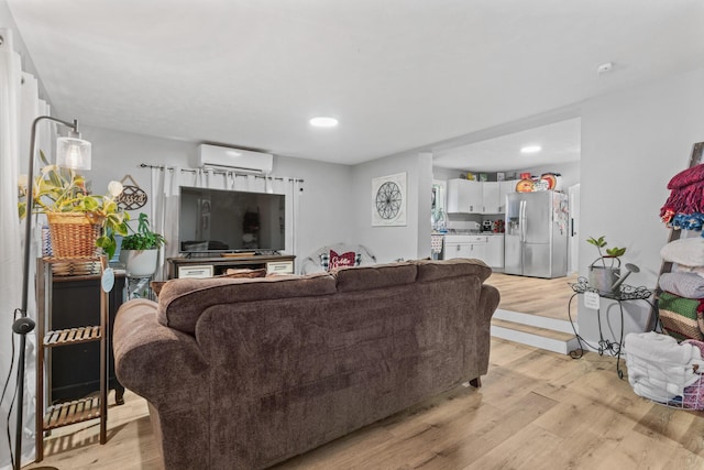 living room with a wall mounted AC and light hardwood / wood-style floors