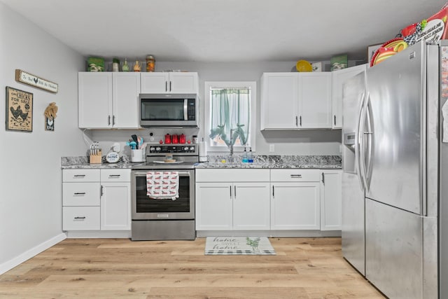 kitchen featuring light stone countertops, light hardwood / wood-style floors, white cabinets, and appliances with stainless steel finishes