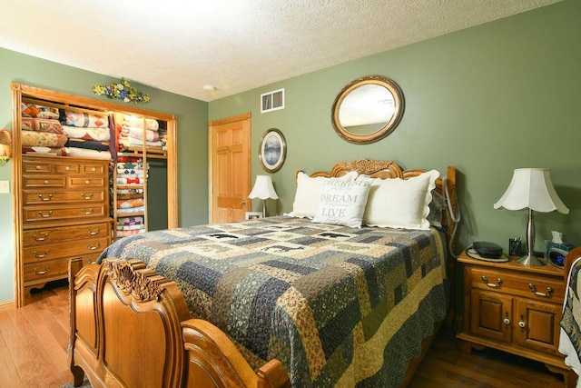 bedroom with visible vents, a textured ceiling, and wood-type flooring