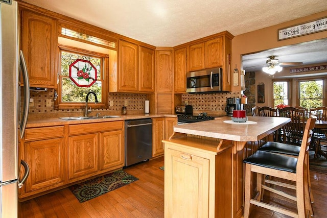 kitchen featuring sink, a breakfast bar, stainless steel appliances, tasteful backsplash, and light wood-type flooring