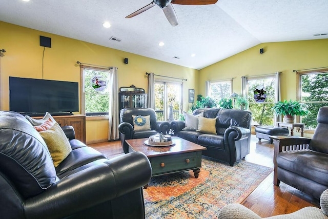 living room with visible vents, ceiling fan, lofted ceiling, light wood-style floors, and a textured ceiling