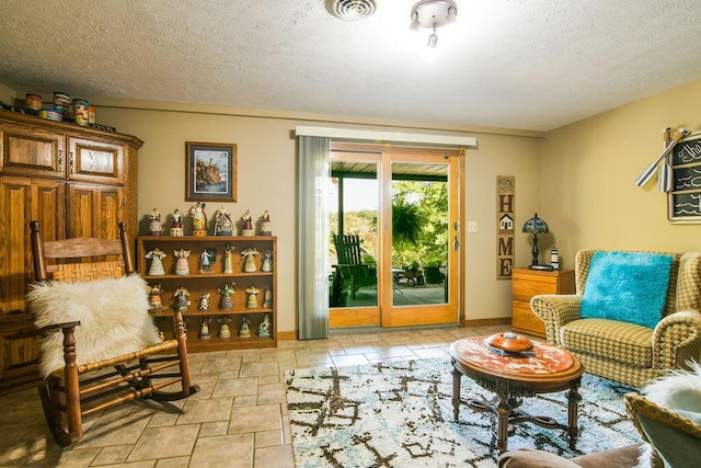 living area with stone finish floor, baseboards, visible vents, and a textured ceiling