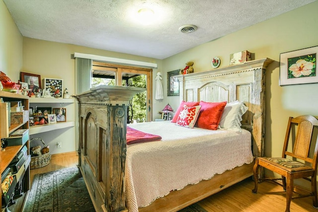 bedroom with hardwood / wood-style floors, access to exterior, and a textured ceiling