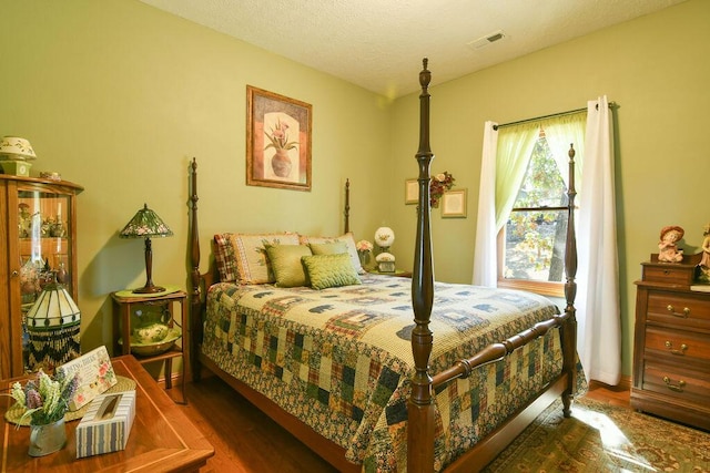 bedroom featuring wood finished floors, visible vents, and a textured ceiling