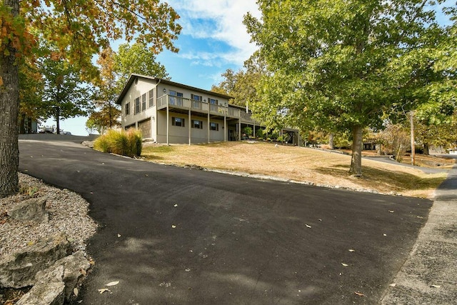 view of front of house with aphalt driveway, a front lawn, a wooden deck, and an attached garage