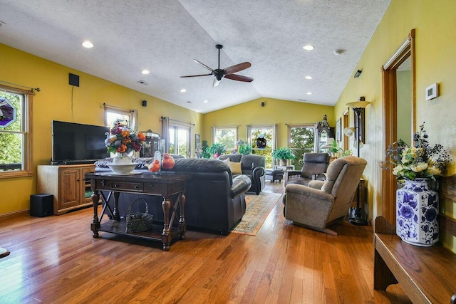 living room with hardwood / wood-style flooring, ceiling fan, lofted ceiling, and a textured ceiling