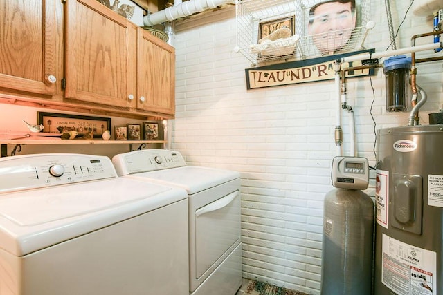 laundry room with cabinet space, brick wall, electric water heater, and independent washer and dryer