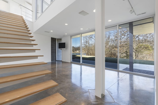 stairway with concrete flooring, expansive windows, and a healthy amount of sunlight