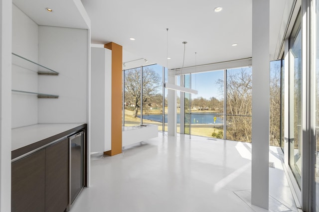 interior space with a water view, a healthy amount of sunlight, and dark brown cabinets